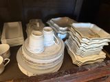 a lot of plates and cups sitting on a dresser
