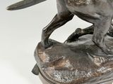 bronze statue of a dog on a rock on a white background