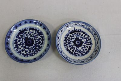 pair of blue and white plates with designs on them sitting on a table