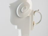 a white vase with a cup shaped like a man ' s head