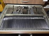 knives and spoons are sitting in a metal tray on a counter