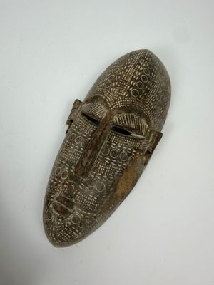 gros plan d'un masque en bois sur une surface blanche