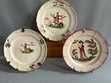 trois assiettes ornées de motifs sont posées sur un support en bois
