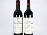 two bottles of red wine sitting next to each other on a white surface