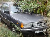 a car that is parked in the grass near a tree