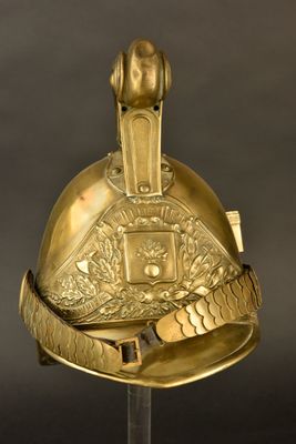 un vieux casque orné d'une décoration dorée, posé sur un socle