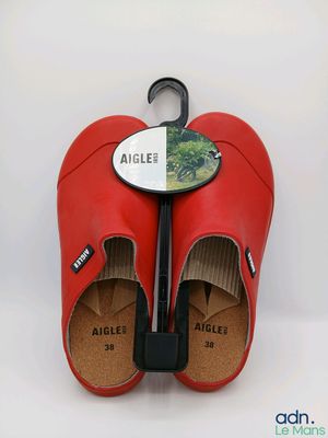 une paire de sabots en cuir rouge auxquels est fixé un parapluie