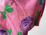 purple and green flowers are painted on a pink dress with green leaves