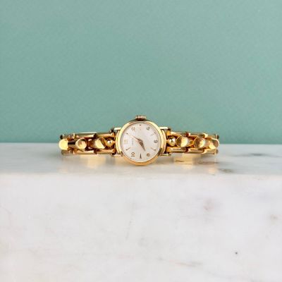 une photo d'une montre en or posée sur un plan de travail en marbre
