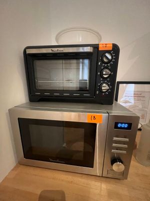 a microwave sitting on top of a counter next to a cup