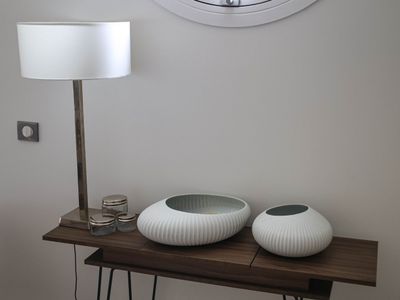 two white vases sitting on a table with a clock on the wall