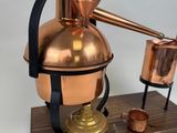 an image of a copper pot with a wooden base and a pipe