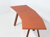 un bureau orange avec deux pieds en bois et un plateau incurvé