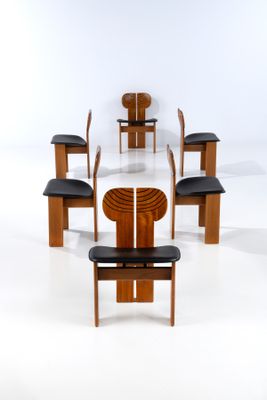 Plusieurs chaises et une table sont disposées en cercle sur une surface blanche.