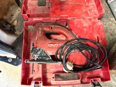 une boîte à outils rouge contenant des outils, posée par terre