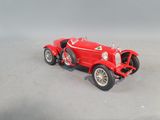 a red toy car that is sitting on a gray surface