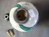 a white vase with a green design on it next to a bullet