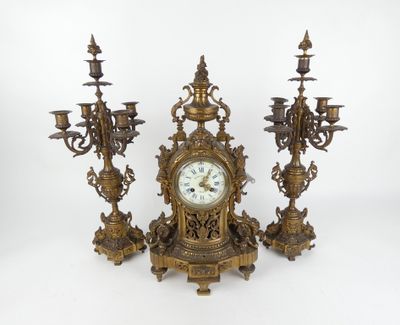 une horloge posée sur une table à côté de trois chandeliers