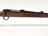 le fusil repose sur un support transparent posé sur une surface blanche