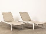 pair of lounge chairs with woven seats in the middle of a concrete floor