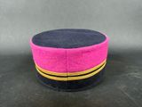 pink and black hat with gold stripes on a black surface