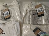 three white nike t - shirts in plastic bags on a table