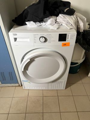 une machine à laver blanche posée sur une pile de vêtements