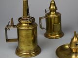 three antique brass teapots and a saucer on a table