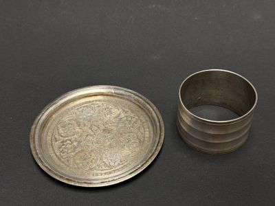 an old silver plate and a silver cup on a black surface