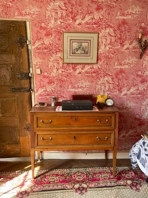 un lit et une commode dans une chambre dont l'un des murs est rouge