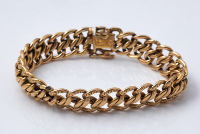 a close up of a gold bracelet on a white surface