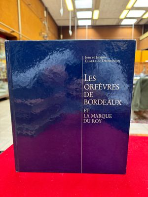 Le livre est posé sur une table rouge devant la bibliothèque.