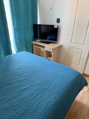 un lit avec une couette bleue et une télévision à écran plat dans un coin