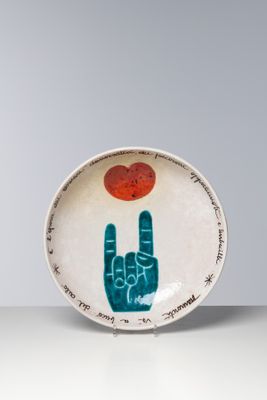 une petite assiette sur laquelle sont peints une main et un cœur