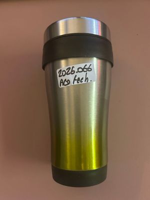 une tasse à café sur laquelle est collé un autocollant, posée sur une table