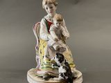 a figurine of a boy and a dog sitting on a chair