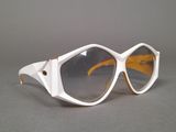 pair of white sunglasses on a gray surface with a gray background