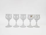 four wine glasses are lined up in a row on a white surface