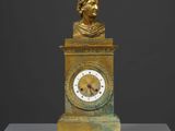 une horloge en or surmontée d'un buste