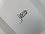 someone is holding a white plate with a black design on it