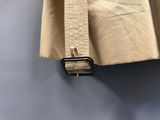 un gros plan sur une veste beige ornée d'une boucle noire