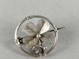 silver plated flower broochle on a white surface