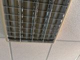 une bouche d'aération au plafond, au milieu d'une pièce équipée d'un ventilateur de plafond