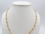 a gold beaded necklace on a mannequin neck