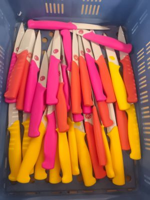 de nombreux couteaux de différentes couleurs dans un panier en plastique