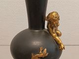 a black vase with a gold decoration on it