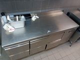 stainless steel counter top in a commercial kitchen with two bins of cleaning supplies