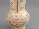 un petit vase orné d'une inscription, posé sur une table