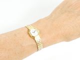 wrist shot of a woman wearing a gold watch and bracelet