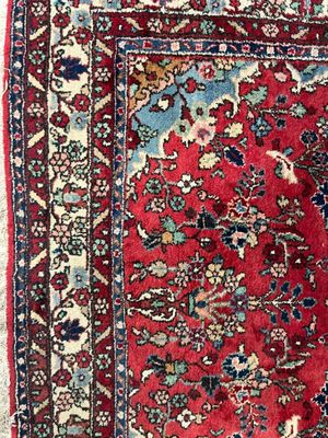 un tapis persan ancien à fond rouge et bordure bleue